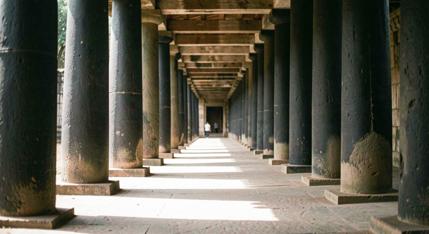 Enfilade de colonnes dans une galerie de temple, alternance régulière de piliers sombres et de trouées de lumière au sol