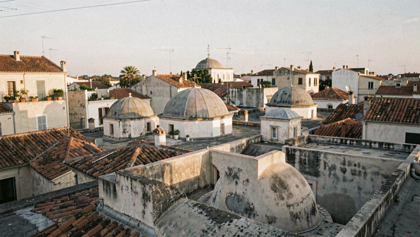 Enchevêtrement de petites coupoles et de terrasses vu depuis un toit en fin de journée, ombres longues entre les volumes