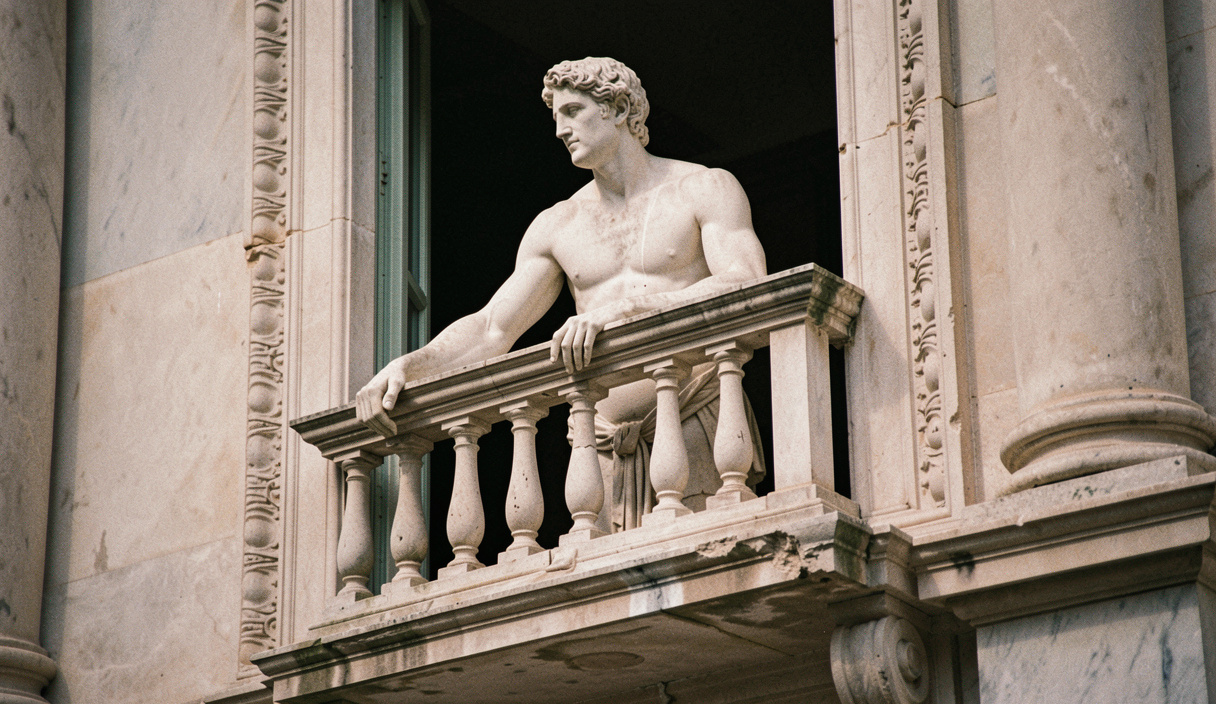 Statue d'atlante soutenant un balcon, l'épaule et le visage éclairés de côté, le reste du portail dans l'ombre
